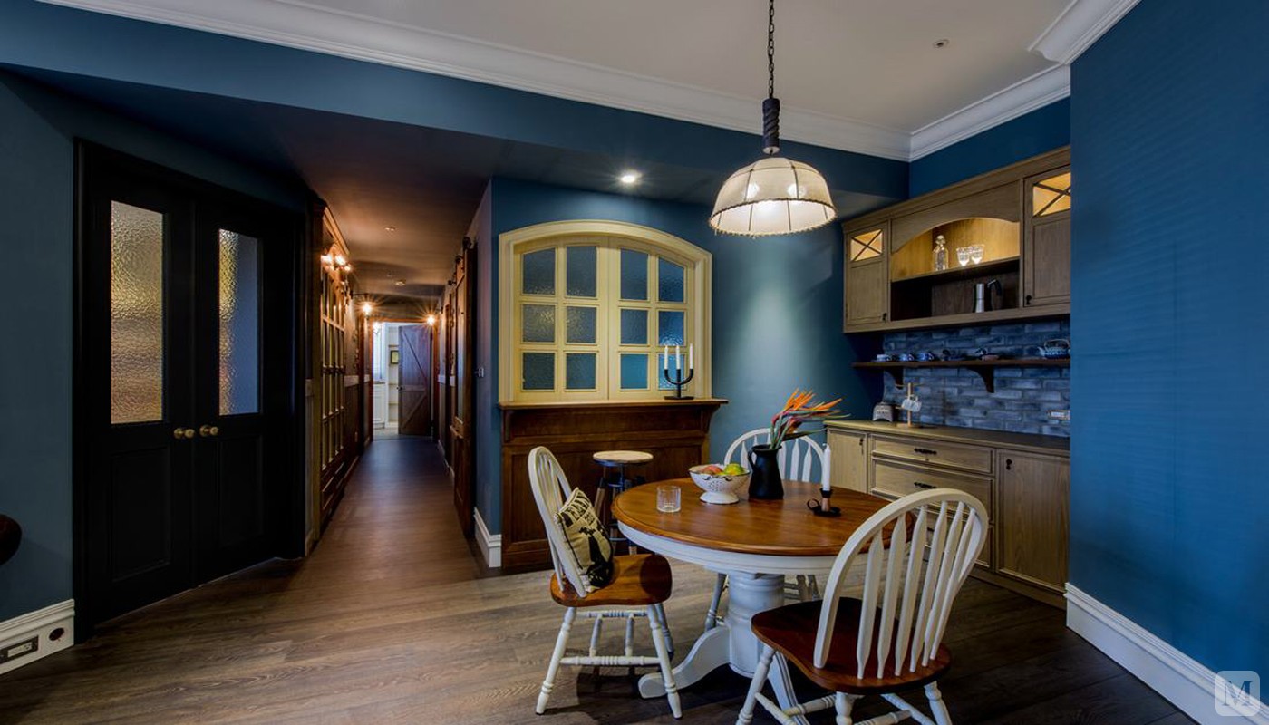 客餐厅及走廊的部分，以蓝色作为空间主色系，佈满了牆面及天花板，
柜子及木头的部分刷上的较深的颜色，并作仿古处理，地板也使用深咖啡色来搭配。
客厅主牆面以粗旷立体的深红色砖型文化石做拼贴，呈现古朴的感觉，一旁的壁炉牆面，用特殊漆来营造历史感，
餐厅壁柜的牆面上，则使用灰色砖型文化石表现，搭配牆面的漆色，恰到好处。