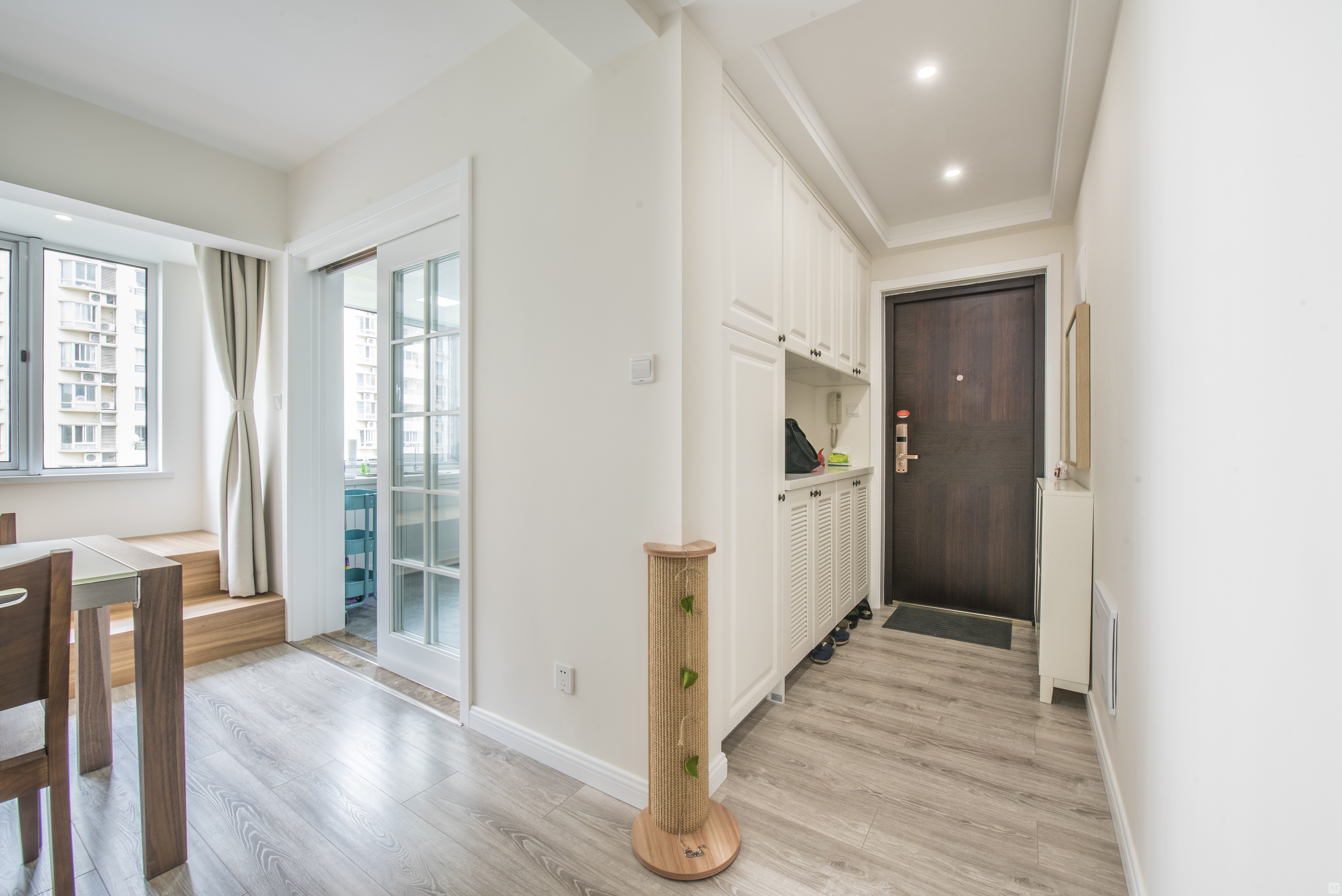 在入户处设计一到顶的白色玄关衣帽柜,除了兼具收纳和展示两个功能以