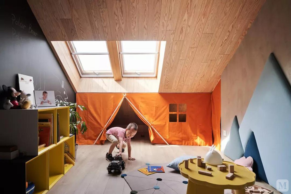 儿童房尚未布置床铺，以橙色幕帘遮挡了木质天花与墙面接壤的突兀感，同时也打造出一个简单方便的储物间，满地的玩具一瞬间就能收拾好。
