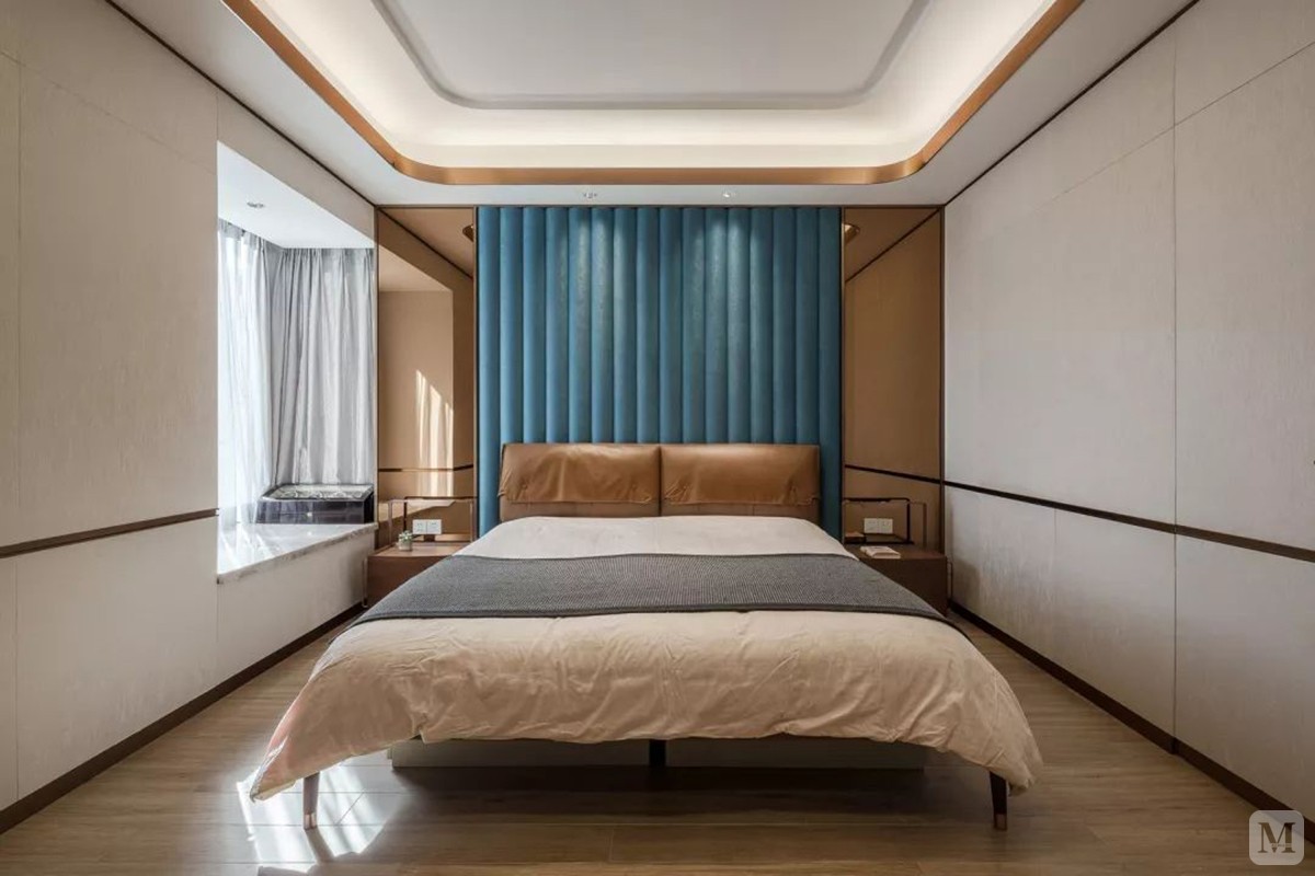 卧室床头墙的蓝色波浪型软包，结合棕色床头靠背，冷暖交融的空间，结合温馨舒适的床单搭配，显得满满的舒适与温馨。